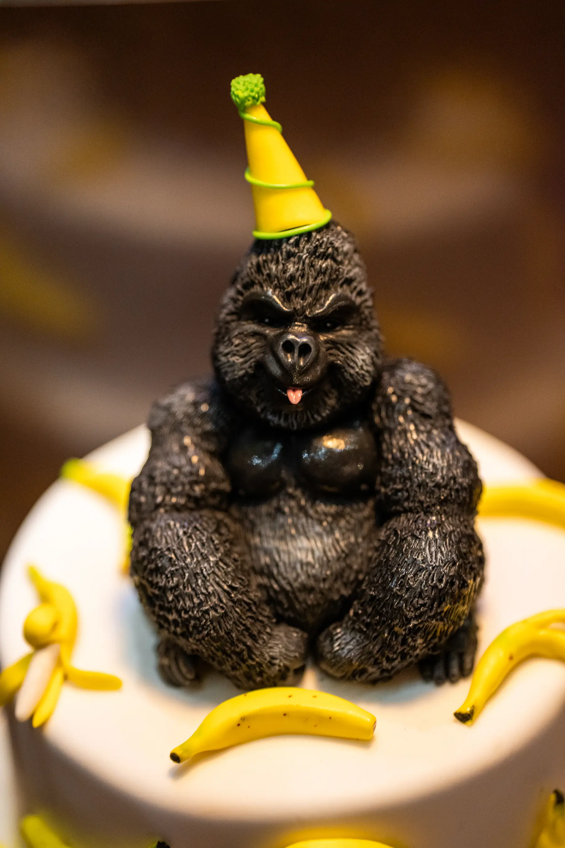 A birthday cake topped with a gorilla in a party hat and bananas at Iguazu Athens