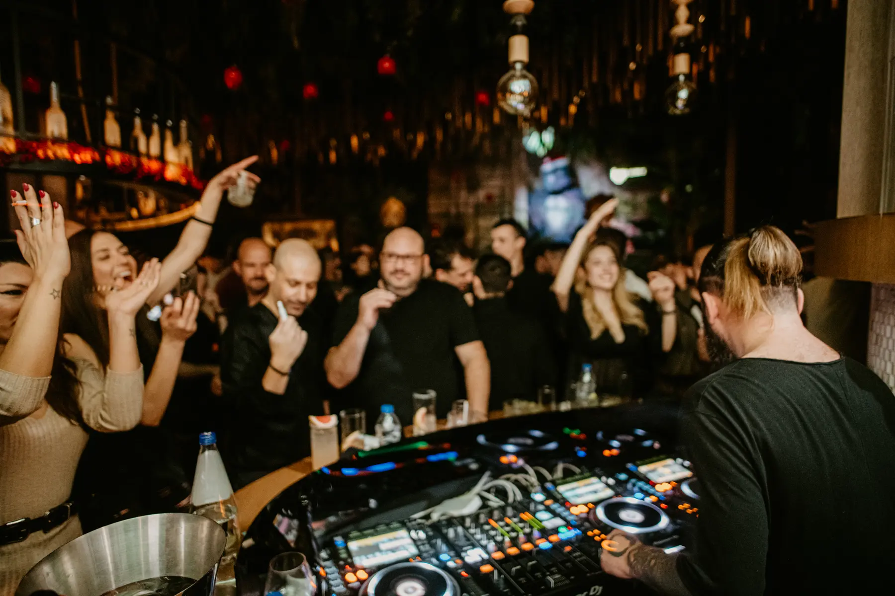 Hands in the air at the DJ booth during a party at Iguazu Athens