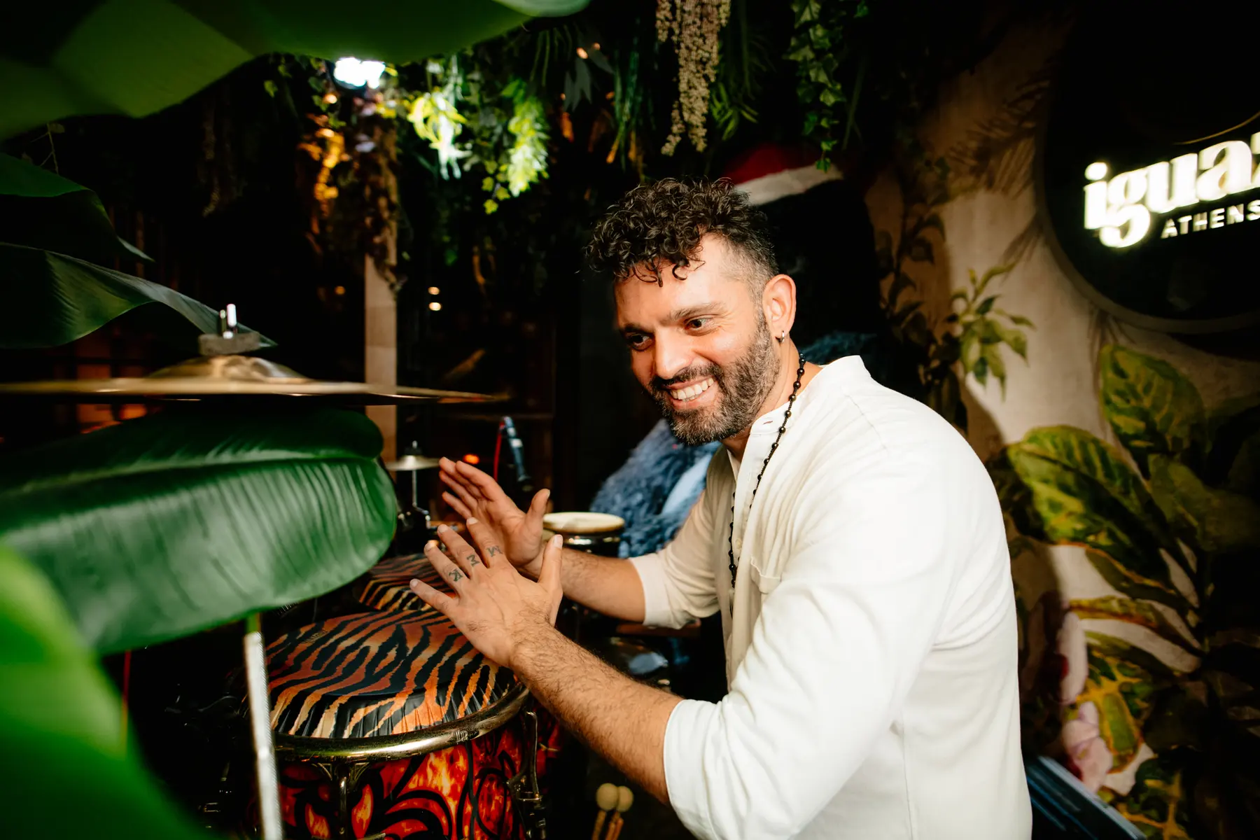A percussionist playing between the plants at a party at Iguazu Athens