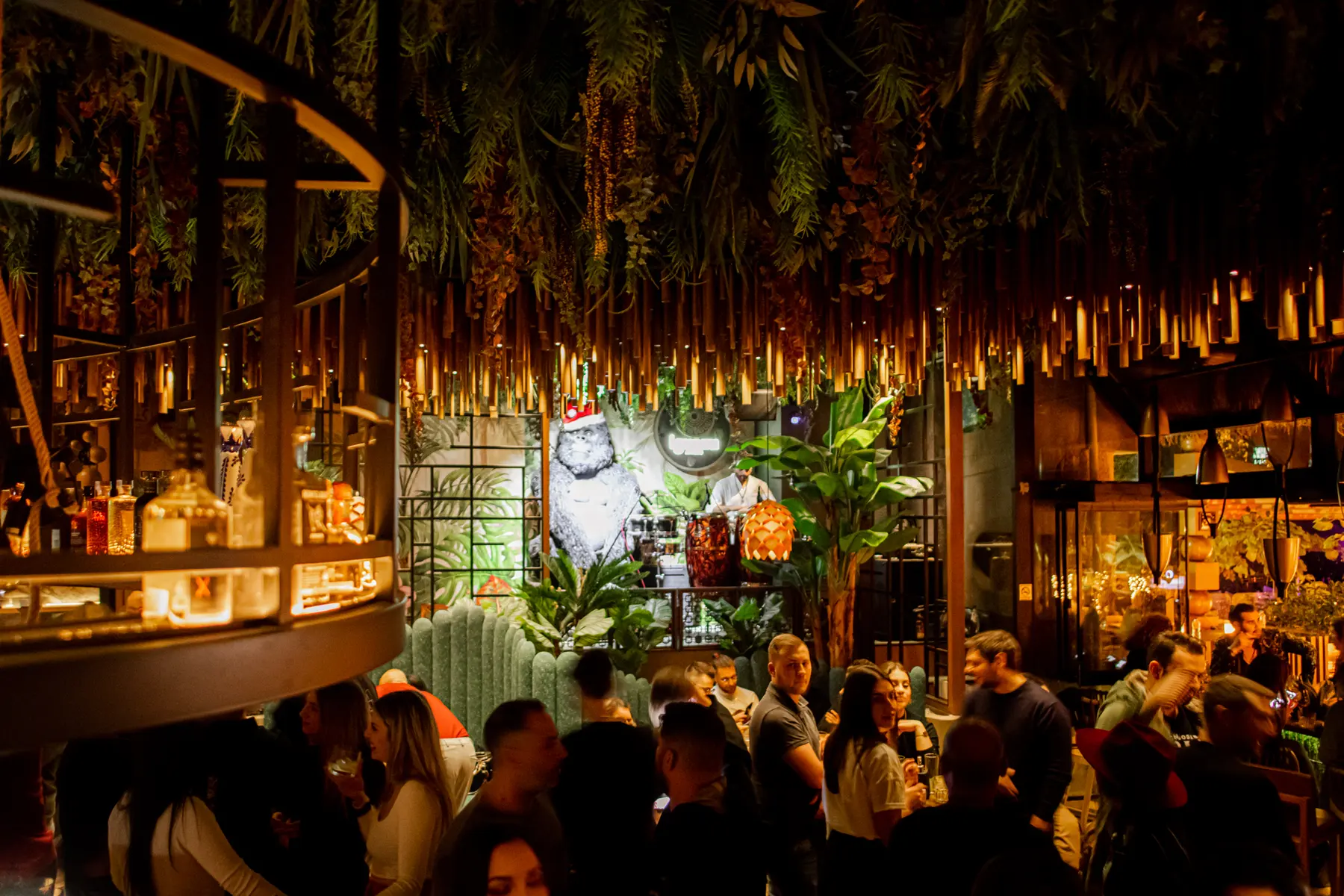 A full house at Iguazu Athens on a party night, guests under the hanging bamboo and plants