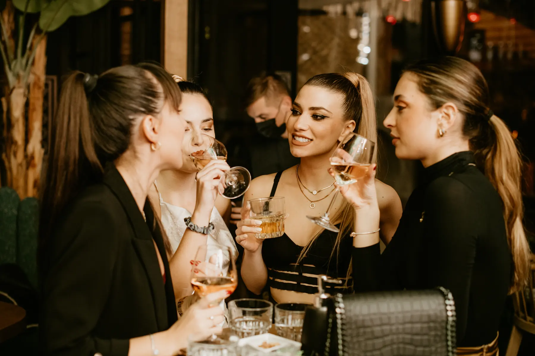 Four friends raising glasses at a party at Iguazu Athens