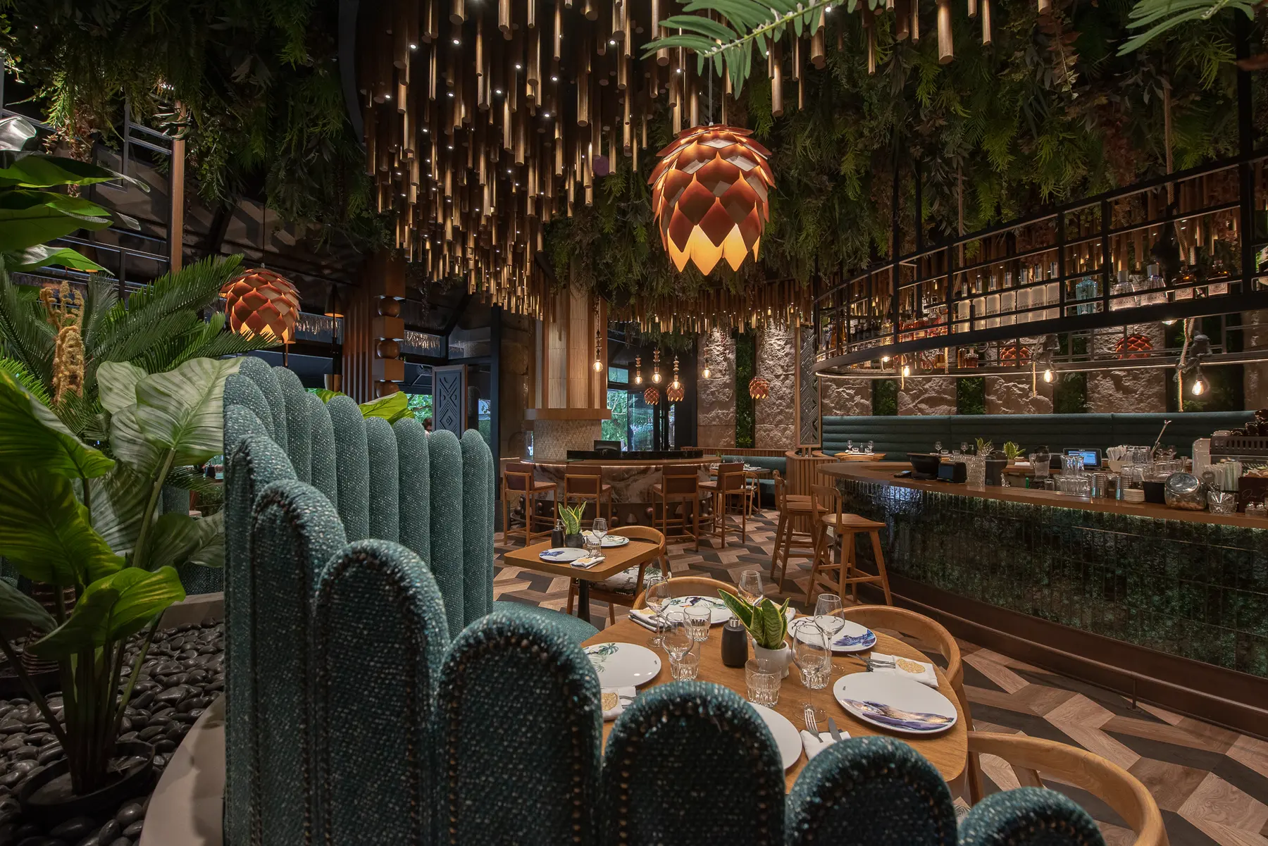 Green banquette seating under hanging plants at Iguazu Athens