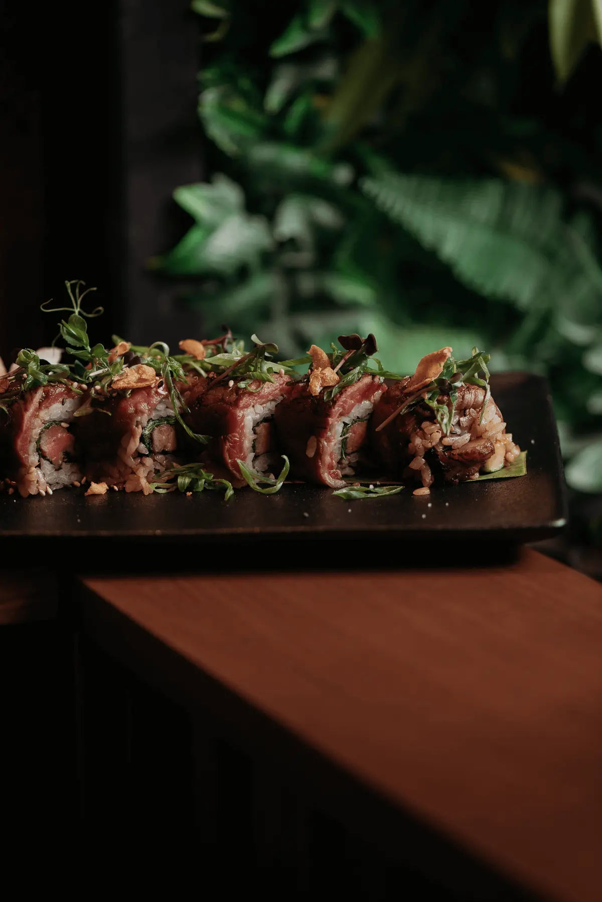 Seared-topped sushi roll on a dark board at Iguazu Athens